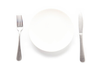 Empty white ceramic plate, knife and fork on a white table. For food, advertising space.