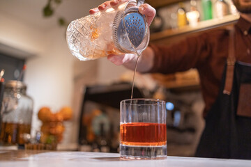 copo de Negroni sendo feito por barman.