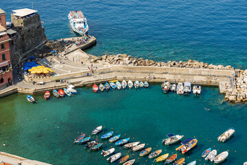 Aerial view of the small port of the ancient Vernazza village with small boats moored and the ferry station. Cinque Terre National park in Liguria, La Spezia, Italy, Europe. UNESCO world heritage site - obrazy, fototapety, plakaty