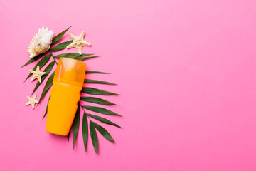 Sunscreen spray bottle. Bottle with sun protection cream and sea shells with tropical green leaf on color background, top view