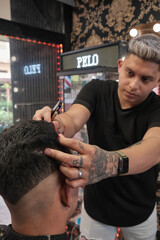 Young handsome man in barbershop having a haircut