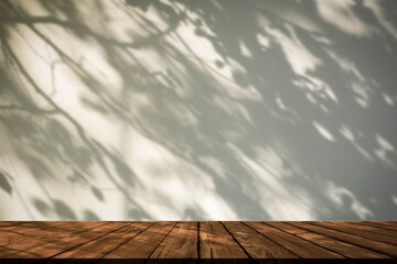 Shadow table background. White wall with shadows plants and tree in sunlight with wooden rustic...