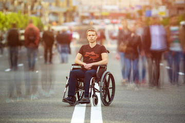 The invalid man sit in the wheel chair at the road with a people stream