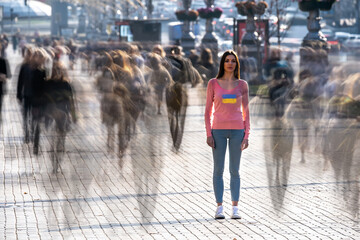 The young woman stands in the middle of crowded street.