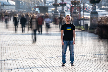 The young man stands in the middle of crowded street.