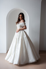 Fototapeta premium Beautiful bride posing in wedding dress in a white photo Studio.