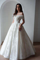 Fototapeta premium Beautiful bride posing in wedding dress in a white photo Studio.