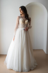 Fototapeta na wymiar Beautiful bride posing in wedding dress in a white photo Studio.