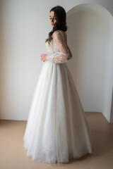 Fototapeta na wymiar Beautiful bride posing in wedding dress in a white photo Studio.