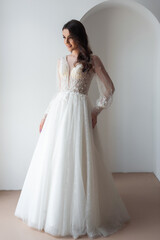 Fototapeta premium Beautiful bride posing in wedding dress in a white photo Studio.
