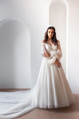 Full length portrait of young beautiful woman wearing white wedding dress. Elegant bride standing and posing