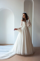 Full length portrait of young beautiful woman wearing white wedding dress. Elegant bride standing and posing