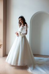 Fototapeta premium Full length portrait of young beautiful woman wearing white wedding dress. Elegant bride standing and posing