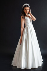 Fototapeta premium Charming young bride in luxurious wedding dress. Pretty girl in white. Emotions of happiness, laughter and smile, gray background
