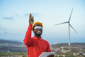 African engineer man using futuristic augmented reality glasses on a windmill farm - Focus on face