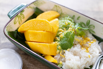Coconut Flavored Sticky Rice with Ripe Mango on wood dish, Popular Thai desserts on summer.