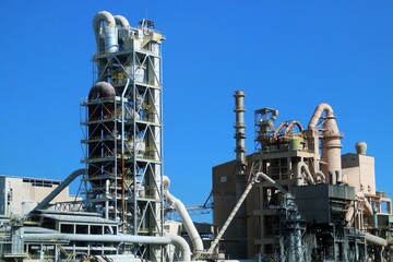 Fototapeta premium Instalaciones industriales de una cementera en un día soleado. Tuberías, depósitos, escaleras y estancias de un complejo industrial en Valencia, España.