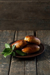Baked pies on a brown clay plate on a wooden table