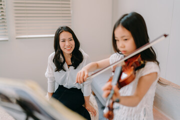 自宅でバイオリンの練習をする母と娘