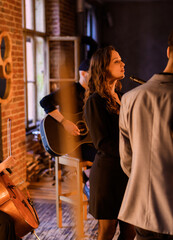 Beautiful young vocalist sings on the background of a band and orchestra in a loft interior