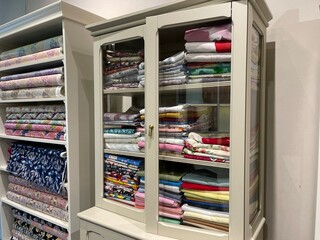 A collection of colorful fabrics with various motifs in the wardrobe. A clothing store wardrobe with multi-storey shelves looks luxurious with a design like a minimalist home interior.
