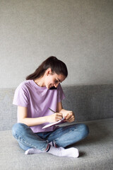 Fototapeta premium A young woman holding a cell phone nearby, talking on the phone with her boss, writes in a notebook