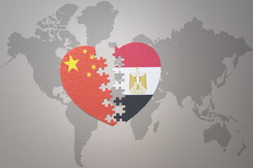 puzzle heart with the national flag of china and egypt on a world map background. Concept.