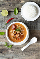 Top view of traditional Thai food. Thai and lao traditional soup - tom yam with seafood on a wooden table with chili, kaffir, lime and coriander.