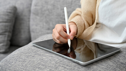 Female sitting in living room, using digital tablet touchpad