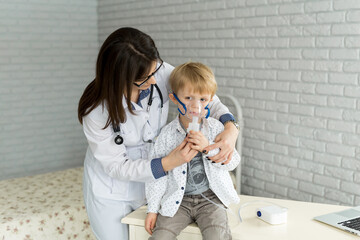 .Medical doctor applying medicine inhalation treatment on a little boy with asthma inhalation...