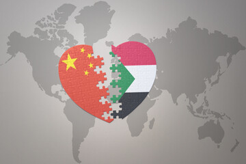 puzzle heart with the national flag of china and sudan on a world map background. Concept.