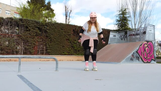 Happy young woman learning to skate in the park