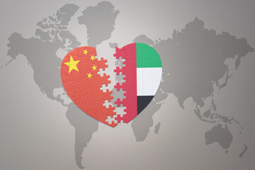 puzzle heart with the national flag of china and united arab emirates on a world map background....