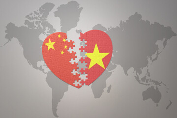puzzle heart with the national flag of china and vietnam on a world map background. Concept.