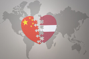 puzzle heart with the national flag of china and latvia on a world map background. Concept.