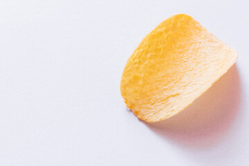 top view of single potato chip with salt on white