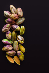 Obraz premium top view of green and salty pistachios without shell isolated on black