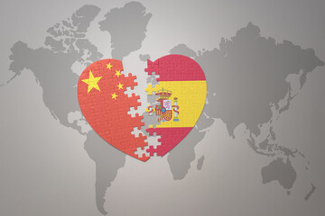 puzzle heart with the national flag of china and spain on a world map background. Concept.