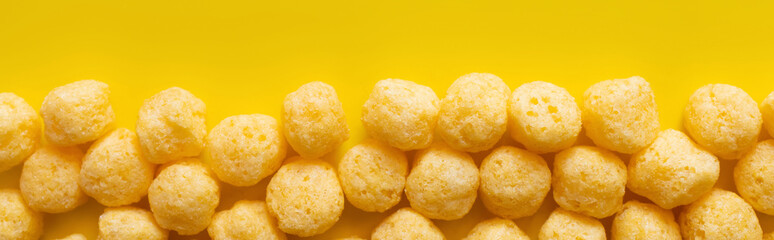 top view of puffed and tasty cheese pops on yellow, banner - obrazy, fototapety, plakaty