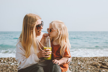 Family vacations child drinking smoothie with mother on beach travel outdoor healthy lifestyle mom and daughter walking together summer trip