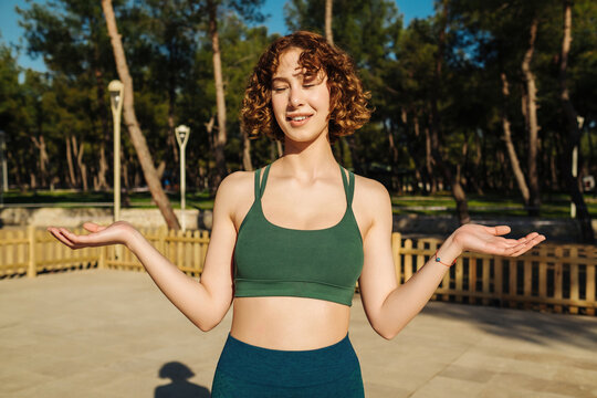 Young redhead woman wearing green sports bra clueless and confused with open arms, no idea and doubtful face.