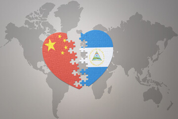 puzzle heart with the national flag of china and nicaragua on a world map background. Concept.