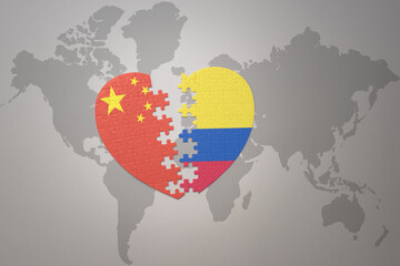 puzzle heart with the national flag of china and colombia on a world map background. Concept.