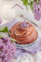 Traditional fresh cinnamon buns on a table with milk bottle and lilac flowers. Kanelbullar - swedish cinnamon rolls.