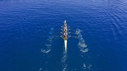 Aerial drone photo of sport canoe operated by team of young trained athletes in deep blue Aegean sea