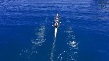 Aerial drone top down photo of sport canoe operated by team of young women in deep blue calm sea...