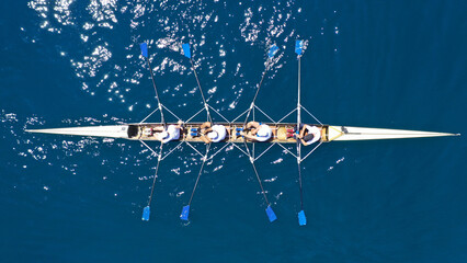 Aerial drone photo of sport canoe operated by team of young trained athletes in deep blue Aegean sea