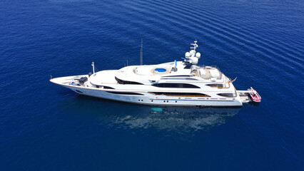 Aerial drone photo of large yacht with wooden deck anchored in Aegean island deep blue sea