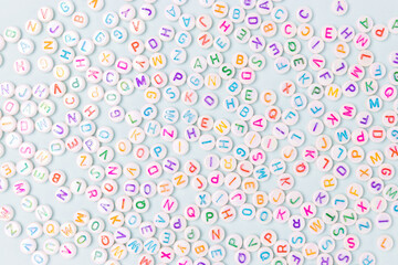 Beads with letters scattered on a blue pastel background.