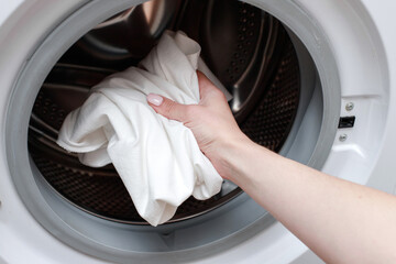 Put white clothes in the washing machine for washing. close-up